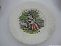 Full view of antique child's porcelain plate showing embossed floral border and central hand painted transfer design with young girl and cat.