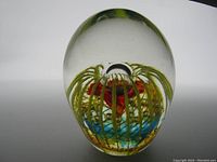 Front view of the glass paperweight showing the internal design with yellow lines and red core.