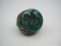 Front view showing the large engraved green stone with bird design on the ring face.