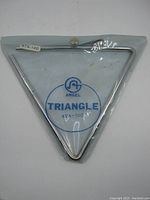 Triangle instrument in original plastic packaging with ATA-100 label visible.