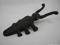 Side angle view showing the beetle form cast iron boot jack with detailed texture and curved antennae.