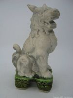 Side view of the white ceramic Chinese Foo Lion Dog sitting on a green base.