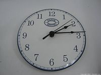 Front view of the Dansk Bistro wall clock showing the clock face, numbers, hands, and logo.