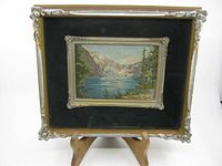 Front view of the framed needlepoint artwork showing mountain lake scene with snow-capped peaks, trees, and water.