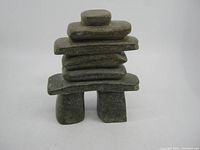 Front-facing view of the carved soapstone Inukshuk against plain background, showing stacked stone distinctive form.