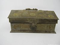 Front angle view showing the embossed floral metal treasure box with latch and handle on the lid.