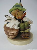 Front view of the M.J. Hummel figurine showing the boy with three white rabbits, one in the basket and two by his side.