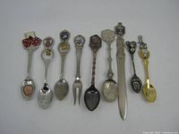 Nine vintage souvenir spoons and one small fork from Las Vegas and Reno, showing different designs, emblems and wear.
