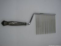 Full view of the cake cutter server showing the sterling silver handle and metal pronged blade.