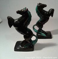 Pair of black and green glazed ceramic horse statues shown on white background