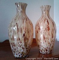 Two large glass vases with brown and cream leopard pattern standing side by side on wooden surface, showing front and side angles.