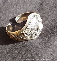 Side and top angle view of a 925 silver adjustable cuff bracelet with intricate engraved patterns and a central blue aquamarine stone.