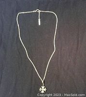 Full view of the 16 inch silver chain necklace with visible flower pendant against black background.