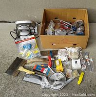 Photo showing Skil saw, various tools including a DEWALT saw blade, putty knives, electrical hardware, switch plates, and a box cutter