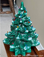 Full frontal view of the ceramic Christmas tree showing overall shape, color, and light bulb decorations.