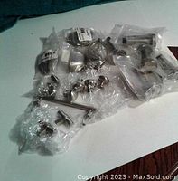 Photo showing multiple chrome hardware pieces packaged separately including drawer pulls, handles, and door stoppers laid on a flat surface.