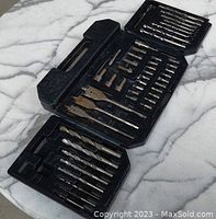 Photo showing entire drill bit set in open black plastic case on marble surface with various bits organized by type.