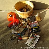 Overview of tools laid out on ground including orange gas can, basket with tools, clamps, hand saws, and rotary tool