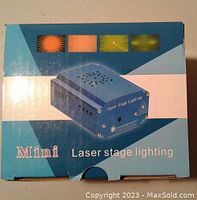 Box of the mini laser stage lighting showing blue metal device and laser light patterns.