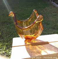 Murano glass bowl displayed outside on wooden surface, showing amber glass color with folded tip edges and smooth glossy finish.