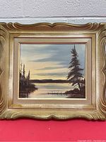 Framed oil painting showing entire artwork and ornate gold frame.