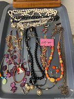 Photo showing a variety of colorful costume jewelry including beaded necklaces, earrings, brooch, and charms spread out on a tray.