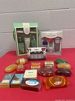 Lot contents showing all three gift sets and 14 assorted bar soaps arranged on a pink surface in front of a white wall.