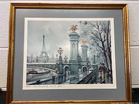 Framed print showing a Paris bridge with Eiffel Tower and people under umbrella.