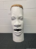 Front view of hand carved wood djembe drum with detailed human face carved and painted white.