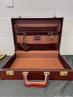Open vintage burgundy leather briefcase showing interior compartments, document holders, and leather and fabric lining