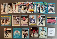 Overview photo of a spread of 43 O.P.C. hockey cards arranged on flat surface showing front of cards with various players and teams from the 1970s.