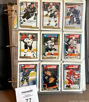 Binder page with nine hockey cards, displaying various players in hockey action, including Super Rookie cards.