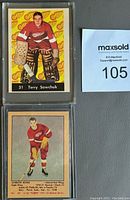 Front view of two hockey insert cards: Terry Sawchuk in goalie gear wearing Detroit Red Wings jersey, and Gordie Howe in red Detroit Red Wings jersey with hockey stick.
