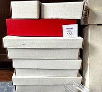 Stack of large white and one red cardboard monster boxes for card storage