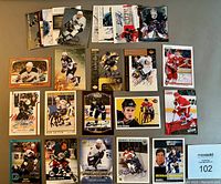 Overview of 25 NHL hockey cards autographed by various players including Richard, Shanahan, Linden, Datsyuk, Carlyle laid out on table.