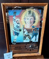 Front view of framed mirror clock depicting Wayne Gretzky in Edmonton Oilers colors in three images, with clock face in the corner.