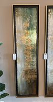 Front view of tall abstract painting on metal panel showing green, beige and gold colors with resin coating, framed in gold-tone frame.
