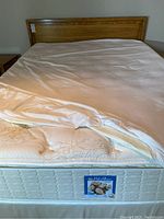 Assembled queen bed showing wood headboard, mattress with sheet