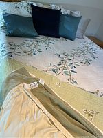 Full queen size bed spread with floral embroidery and assorted pillows arranged on top
