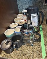Photo showing Bodum French press, large black coffee urn, and assorted coffee mugs arranged on a kitchen counter.