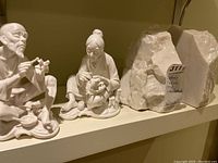 Shows both ceramic figurines and two stone bookends together on a shelf.