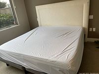 Front view of king size bed with mattress on twin platforms and fabric headboard visible
