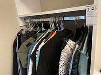 Clothes on hangers including pants, tops, and jackets in varying colors and styles