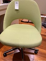 Front view of green fabric chair showing seat, backrest and caster base