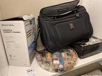 Wide view of the lot showing the Beautural garment steamer box, Travelpro carry-on bag, circular thread organizer, button box, and thread holder.