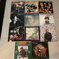 All 11 vinyl album covers displayed on floor, showing titles and artwork including KISS, George Harrison, Bob Dylan, The Beach Boys, Jethro Tull, Lennon/Ono