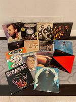 Photo showing all 14 vinyl albums arranged upright with some covers fully visible and others partially visible against a wall.