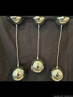 Three chrome pendant bar lights with perforated spherical shades hanging against a dark background.