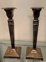 Front view of the pair of silver plated candlesticks showing fluted shaft and square stepped base