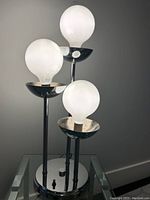 Lamp with all three bulbs off, showing chrome finish and structure.